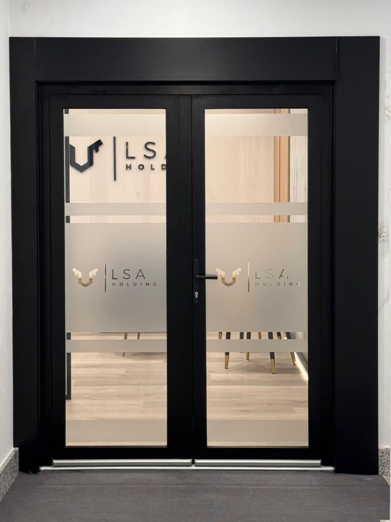 Vinilo translúcido personalizado con logotipo corporativo de LSA Holding aplicado sobre puertas de cristal para privacidad y branding